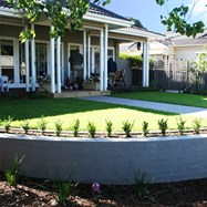Curved brick wall retaining levelled lawn area. 