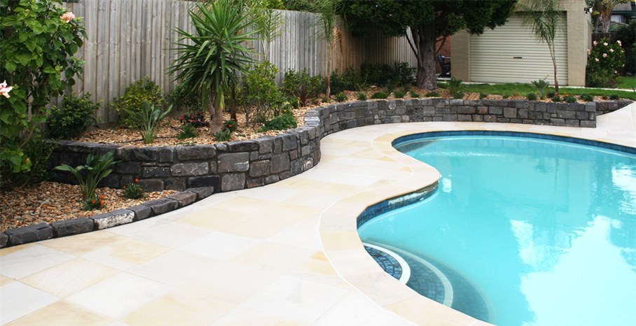 Pool renovation in Melbourne, with new sandstone coping and paving .  Gardens beds retained with bluestone pitchers planted with a tropical feel. pools and landscaping. pool designs and landscaping. backyard pools and landscaping